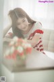 A woman sitting on a couch next to a vase of flowers.