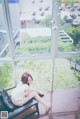 A woman sitting on a bench in front of a window.