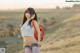 A woman with a backpack standing in a field.