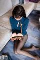 A woman sitting on the floor looking at her cell phone.