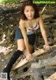 A woman in a bikini top and shorts sitting on a pile of logs.