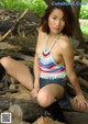 A woman sitting on a pile of logs in the woods.