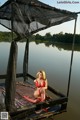 A woman in a red bikini sitting on a dock.