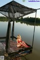 A woman in a red bikini sitting on a dock.