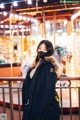 A woman wearing a face mask standing in front of a carousel.