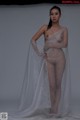 A naked woman standing in front of a white backdrop.