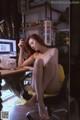 A naked woman sitting at a desk with a cat.