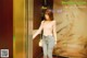 A woman standing in front of an elevator with a handbag.