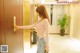 A woman standing in front of a door with a green purse.