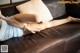 A woman laying on a brown leather couch with her legs crossed.