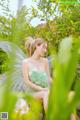 A woman in a green dress sitting in the grass.