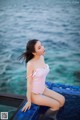 A woman in a pink bathing suit sitting on the edge of a pool.