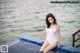 A woman in a white bathing suit sitting on the edge of a swimming pool.