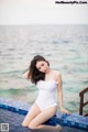 A woman in a white bathing suit sitting on the edge of a pool.