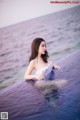 A woman in a white dress sitting in a pool of water.