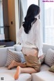 A woman sitting on a couch with her back to the camera.