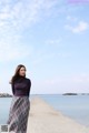 A woman standing on a pier by the water.