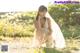 A woman in a white dress crouching down in a field.