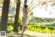 A woman in a white dress is walking in the park.