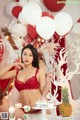 A woman in a red lingerie holding a bunch of white balloons.