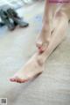 A woman's bare feet with pink nail polish on the floor.