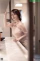 A woman in a pink dress leaning on a counter.