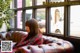 A woman sitting on a couch in front of a window.