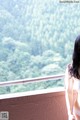 A woman standing on a balcony looking out over a forest.