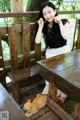 A woman sitting at a wooden table with a cat on the ground.