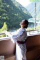 A woman in a white kimono standing on a balcony.