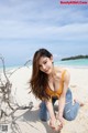 A woman sitting on a sandy beach next to the ocean.