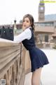 A woman in a school uniform leaning against a railing.