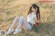 a woman sitting on top of a grass covered field