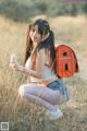 A young woman sitting in a field holding a cell phone.