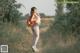 A woman with a backpack walking down a dirt road.