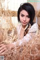 A woman in a white dress sitting in a field of tall grass.