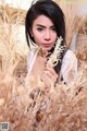 A woman in a field of dry grass holding a flower.