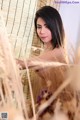 A naked woman standing in a field of tall grass.