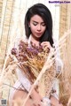 A woman in a white dress holding a bunch of dried flowers.