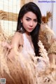 A woman in a white dress sitting in a field of tall grass.