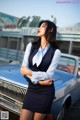 A woman standing in front of a blue car.