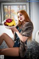 A woman sitting on a chair holding a bowl of fruit.