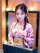 A woman in a pink kimono posing for a picture.