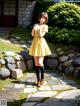 A woman in a yellow dress standing on a stone path.