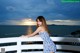 A woman in a blue and white dress standing on a balcony.