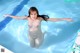 A naked woman in a swimming pool with her arms outstretched.