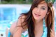 A woman in a blue and green bikini posing by a pool.