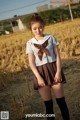 A woman in a school uniform standing in a field.