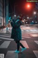 A woman wearing a cat mask standing in the middle of a street.