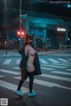 A woman wearing a cat mask crossing the street at night.